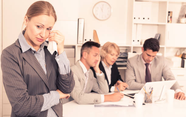 istock Crying woman at office on background with coworkers 944655010