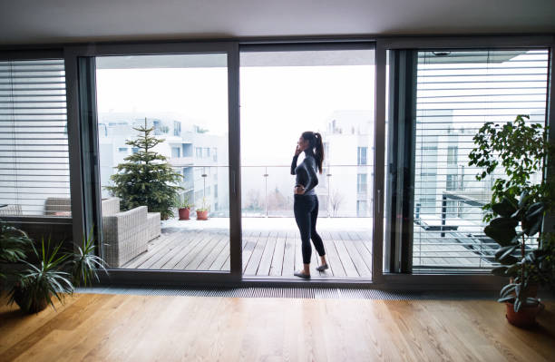 istock Woman by the window with smartphone, making a phone call. 944656696
