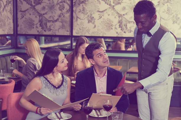 istock African American waiter recommending dishes from restaurant menu 944657400