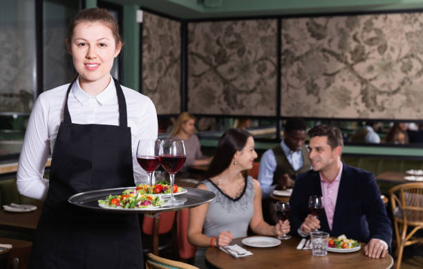 istock Attractive young waitress with serving tray welcoming in restaurant 944657476