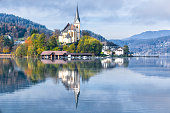 Beautiful church in Augsdorf-Velden, Lake Woerthersee, Carinthia, Austria with majestic reflection on water surface