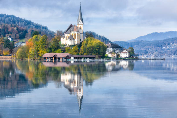 Beautiful church in Augsdorf-Velden, Lake Woerthersee, Carinthia, Austria with majestic reflection on water surface stock photo