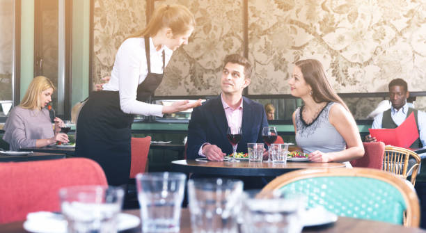 istock Waitress talking with satisfied couple in restaurant 944657630