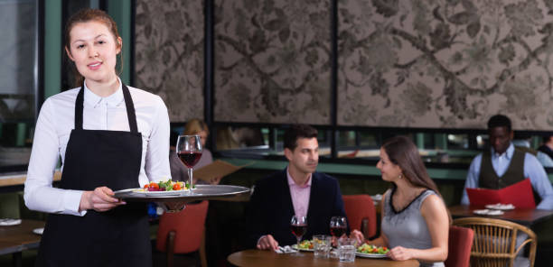 istock Attractive young waitress with serving tray welcoming in restaurant 944657736
