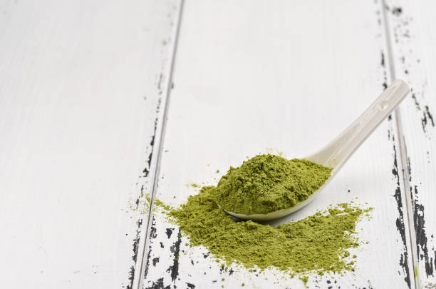 istock Green tea match powder in a white ceramic spoon on white wooden background 944662170