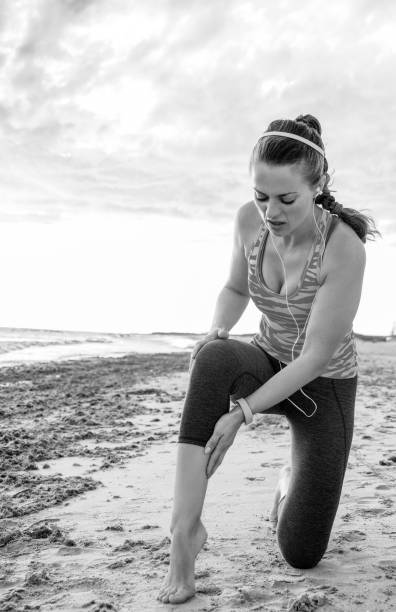 istock healthy active woman on seashore having leg injury 944662280