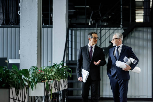 istock businessmen with notepad and blueprints having conversation in office 944663172