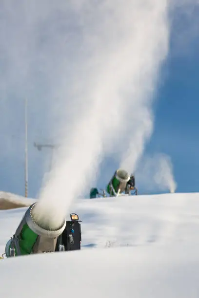 Photo of Snow-machine bursting artificial snow  over a skiing slope