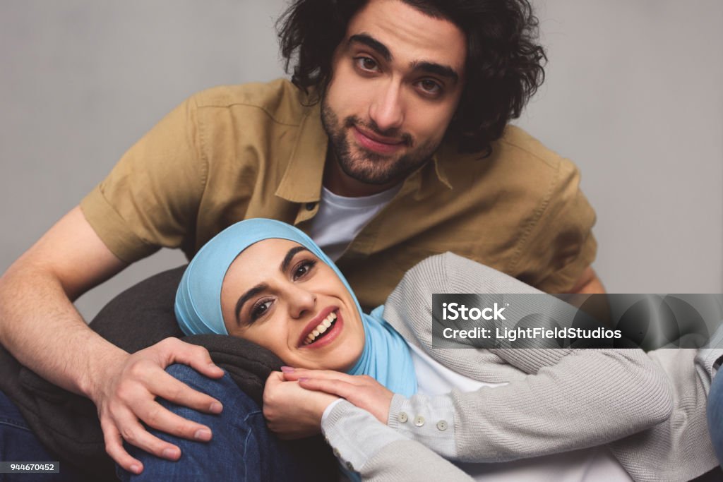 smiling muslim couple looking at camera at home Couple - Relationship Stock Photo