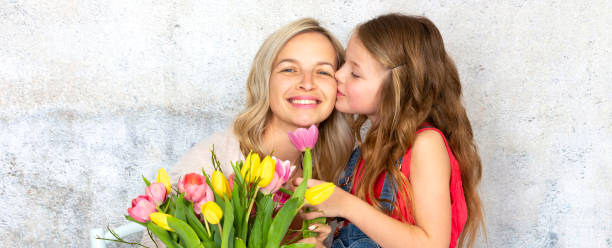 young and blond and pretty mother gets a bouquet of colorful flowers from her daughter on mothers day - single flower bouquet flower holidays and celebrations imagens e fotografias de stock