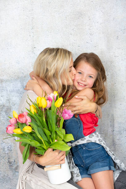 jeune et blonde et jolie mère obtient un bouquet de fleurs colorées de sa fille sur la fête des mères - mothers day mother single flower family photos et images de collection