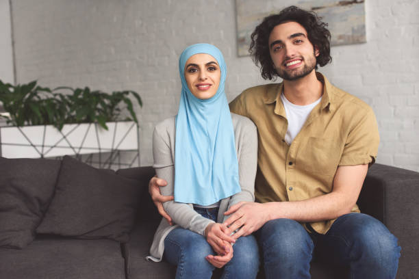 istock smiling muslim couple hugging and looking at camera at home 944672368