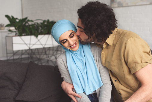 muslim boyfriend kissing girlfriend in hijab at home