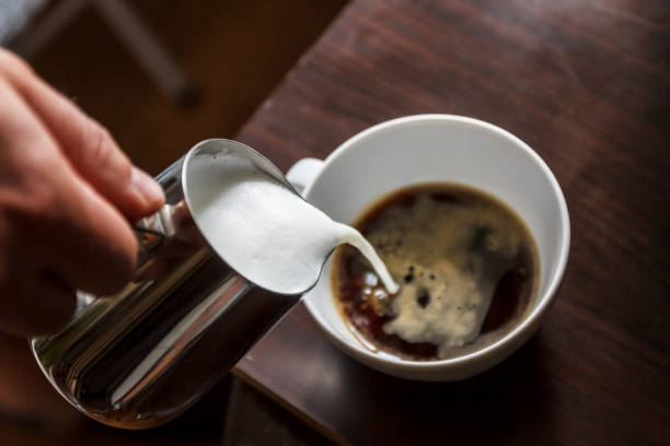 istock man pouring into a cup of coffee with milk 944676766