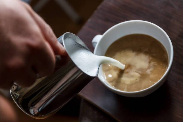 istock man pouring into a cup of coffee with milk 944676772
