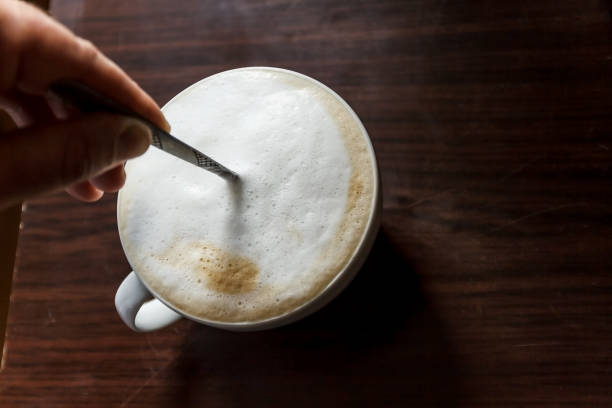 istock Cup of coffee with foam being stirred by a human hand 944676838