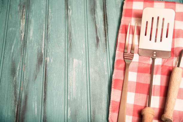 istock Outdoor grilling, BBQ utensils on rustic picnic table. 944677310