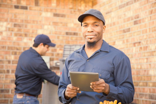 istock Multi-ethnic team of blue collar air conditioner repairmen at work. 944677720