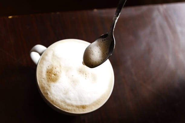 istock Cup of coffee with foam being stirred by a human hand 944677794