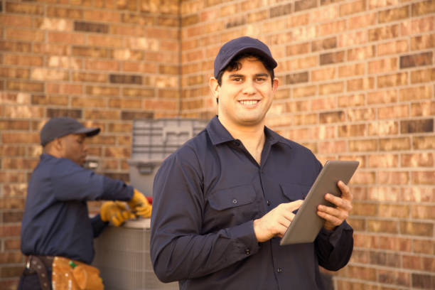 istock Multi-ethnic team of blue collar air conditioner repairmen at work. 944677922