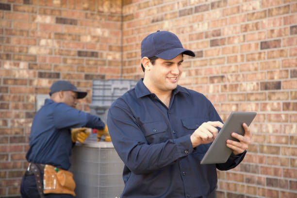 istock Multi-ethnic team of blue collar air conditioner repairmen at work. 944678784