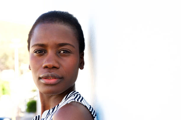 Close up portrait of young black lady leaning to wall outside