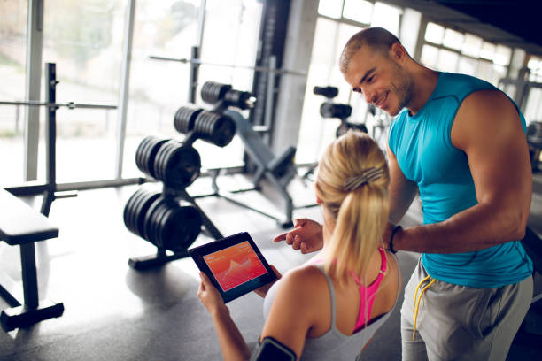 istock Young woman discussing workout progress with fitness instructor 944686620
