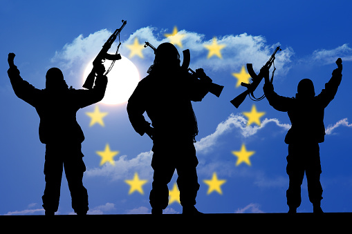 Silhouette of soldier with weapons at sunset. holding gun. Concept of a terrorist. Silhouette terrorists, national flag on background - European Union