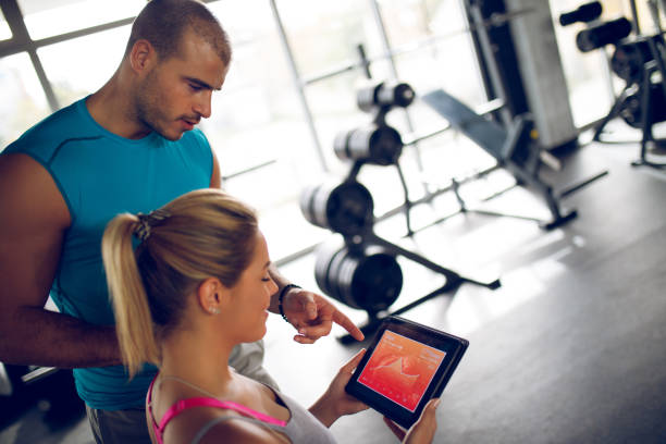 istock Young woman discussing workout progress with fitness instructor 944691004