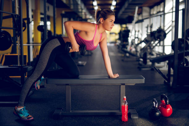 istock Young woman having weight training with dumbbells at gym 944692336