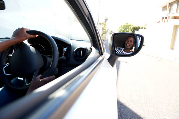 istock Close up smiling black driving car and looking in side mirror 944698444