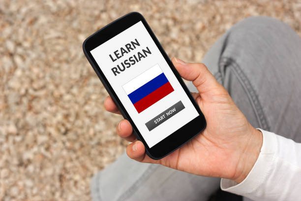 istock Hand holding smart phone with learn Russian concept on screen 944733086