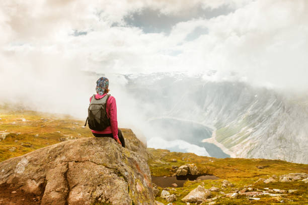 istock Young woman with backpack standing on fjord coast 944734356