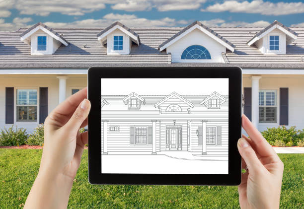 istock Female Hands Holding Computer Tablet with House Drawing on Screen, Photo Behind. 944751274