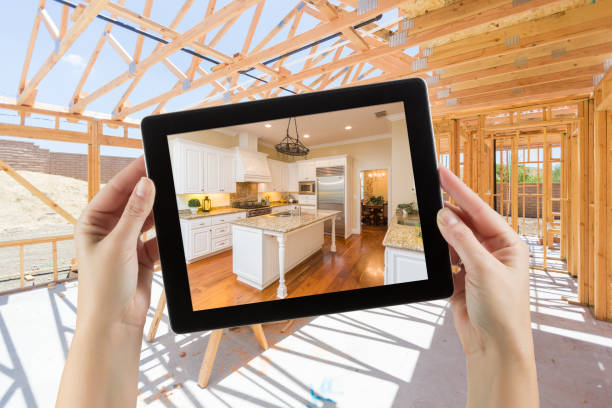 female hands holding computer tablet with finished kitchen on screen, construction framing behind. - home improvement house home interior residential structure imagens e fotografias de stock