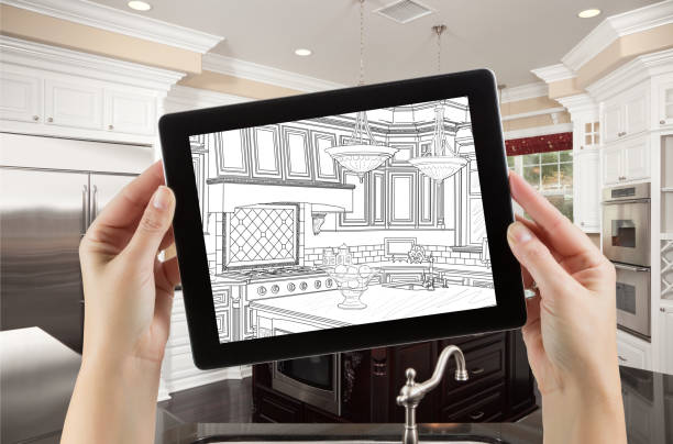 istock Female Hands Holding Computer Tablet with Drawing on Screen of Kitchen Behind. 944751336