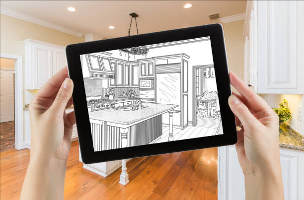 istock Female Hands Holding Computer Tablet with Drawing on Screen of Kitchen Behind. 944751356