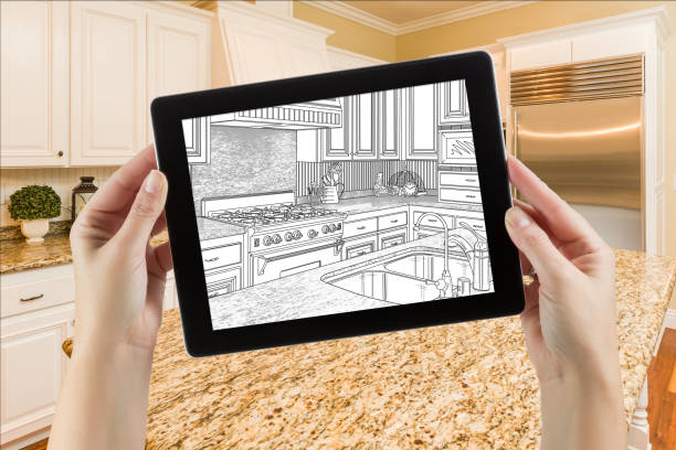 istock Female Hands Holding Computer Tablet with Drawing on Screen of Kitchen Behind. 944751374