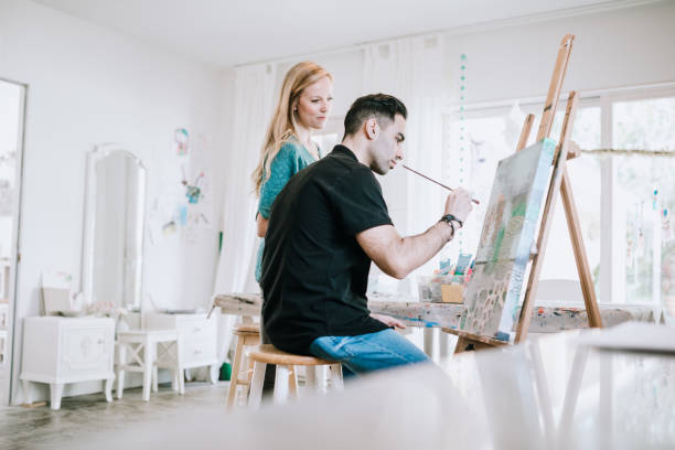 istock Woman Teaching Man Painting at Home Art Studio 944754966