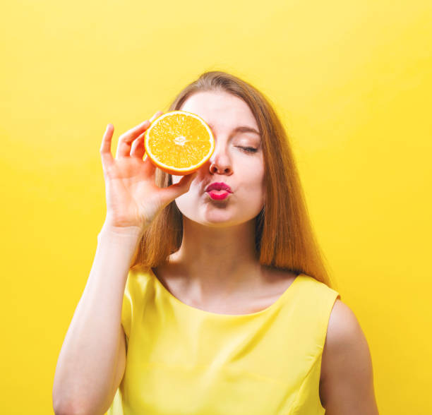 istock Happy young woman holding a half orange 944756572