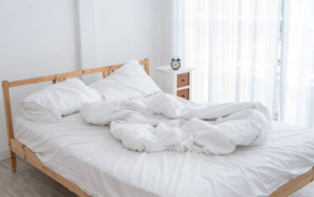 istock White messy bed in a white room in morning without people 944771880
