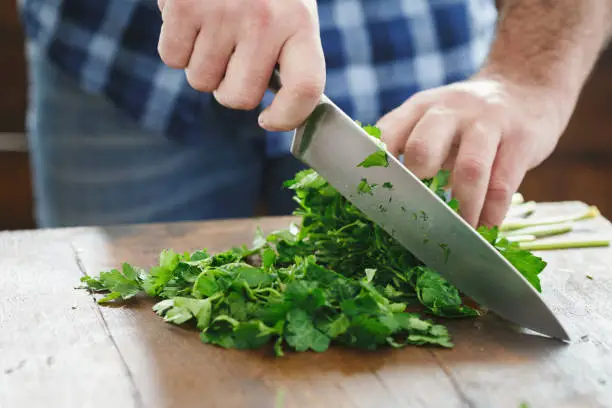 Photo of Close-up male hands chopping fresh parsley