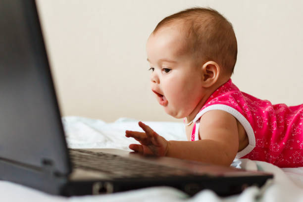 istock Cute baby with laptop on the white bed 944775114