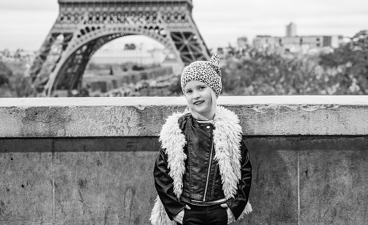 Bold Winter in Paris. Full length portrait of smiling trendy child in the front of Eiffel tower in Paris, France