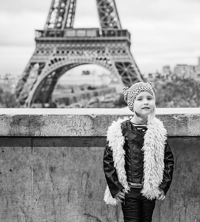 Bold Winter in Paris. Full length portrait of modern child standing against Eiffel tower in Paris, France