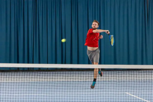 Two Tennisplayers make a match in a tennis hall with blue floor.