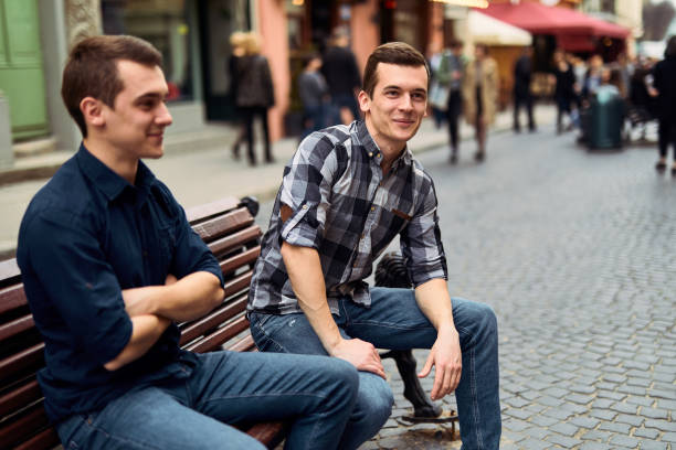 istock Two man sit on bench and talk on the street 944779020