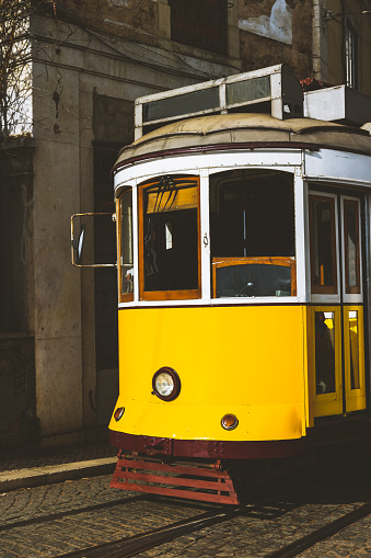 Quaint yellow tram on the rails of old and beautiful street of Alfama District of Lisbon. City touristic landmarks of Lisboa Lissabon.