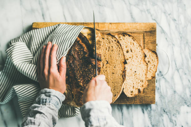 istock Female hands cutting freshly baked sourdough bread 944794758
