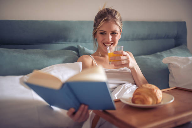 istock Young woman reading a book in bed 944809050